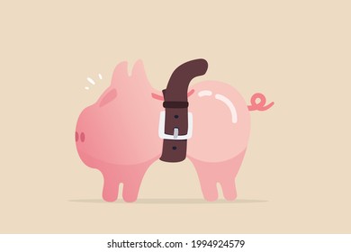 Tighten belt to reduce budget or spending, financial crisis or economic slow down, keep cost and expense low to survive, pink piggybank tighten belt on his belly metaphor of saving cost.