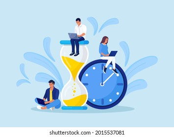 Tiny people and huge hourglass, alarm clock. Team working together with laptops. Time management and business planning. Time is money.  Deadline. Young employees work near the dial of a large watch. - Shutterstock ID 2015537081