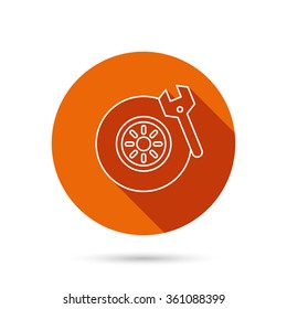 Tire service icon. Wheel and wrench key sign. Round orange web button with shadow.