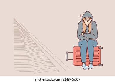 Tired woman sits on suitcase near railway waiting for train and is sad because of lack of money for ticket. Unhappy girl in hood missed train freezes at station alone. Flat vector illustration