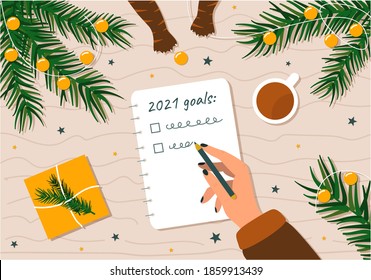 To-do list and goals for the New year. A woman's handwriting plans for the future surrounded by Christmas branches and Christmas decorations and cat paws stealing toys.