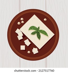 Tofu on wooden plate with soya beans and basil leaves top view