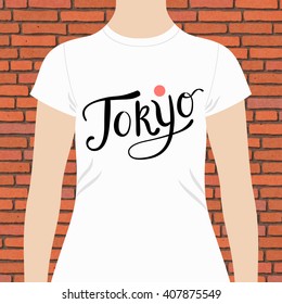 Tokyo t-shirt design template with flowing text and red circle on white modeled closeup against a brick wall, vector illustration