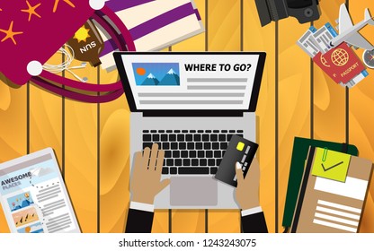 Top down flat view of table with laptop and hand holding the credit card preparing for booking a trip, surrounding with laptop,passport, camera and travel stuffs