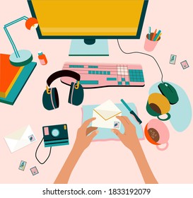 Top view concept of creative hand drawn home workspace.Hands opening mail,holding a stamped envelope.Computer with keyboard,mouse,office supplies on the desktop.The camera,headphones.Art occupation