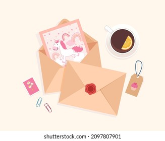 Draufsicht auf den Schreibtisch mit Umschlägen, Postkarte, Briefmarken und Tasse Tee