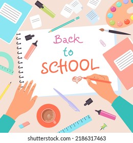 Top view of desk with human hands drawing in notebook. Back to school. Colorful set of school supplies arranged on a desk from top view. 
