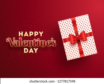 Top view of gift box with stylish lettering of happy valentine's day on glossy red background.