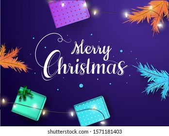 Top view of gift boxes with colorful pine leaves and lighting garland decorated on purple background for Merry Christmas celebration.
