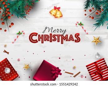 Draufsicht auf eine Steinglocke mit Kiefernblättern, rote Beeren, Zuckerrohr, Sterne und Geschenkbox auf weißem Holzhintergrund für fröhliche Weihnachtsfeiern.