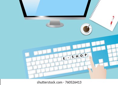 Top view of the office desk with coffee cup, blank paper with pen, computer monitor and keyboard. Hand is touching keyboard with inscription E-shopping