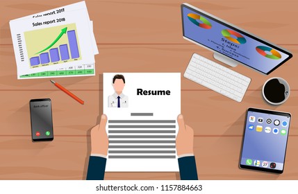 Top view on hands with Resume above desk with laptop,mobile, tablet and other business accessories. Modern business workplace