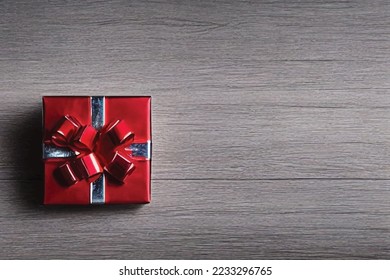 Top view shot of small red paper wrapped gift present box with silver shiny glossy ribbon bow tie