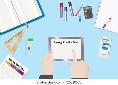 Top view of the student table. Hands of the student are touching tablet with Biology Practice Test. 