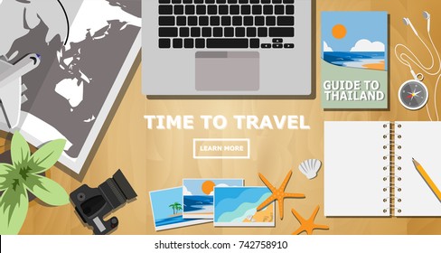 Top view of traveler desk, plan for the trip with with copy space for text on wooden, laptop computer, camera with lens, trekking map, guidebook for Thailand, photos of vacation place.
