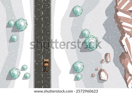 Top view of a two-lane highway running between snow-covered fields. Snow-covered trees and fir trees grow along the road. There are brown rocky mountains in the snow. View from above. Aerial.