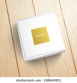 Top view of a white box with a gold inscription Gift on a plank floor. Realistic template for design