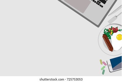 Top view of working desk with laptop, mobile phone, and breakfast with fried egg and sausage with copy space for your own text