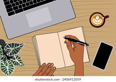 Top view of workplace, hands writing in organizer.