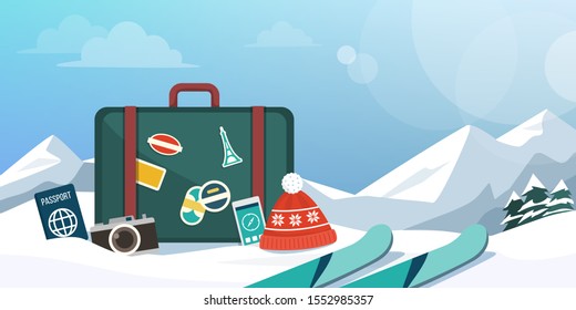 Tourist exploring mountains at winter and skiing, suitcase and travel equipment on the snow