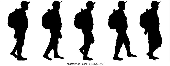 Tourists With Backpacks Walk One After Another. A Group Of Walking Tourists. A Woman In A Sports Cap, A Backpack Behind Her Back, Shorts. An Older Woman Is Hiking. Hiking. Side View, Profile.	