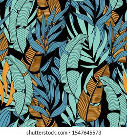 Trend seamless tropical pattern with bright blue and yellow plants and leaves on a dark background. Printing and textiles.   Vector design. Jungle print. Floral background.