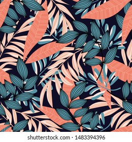 Trending abstract seamless pattern with colorful tropical leaves and plants on blue background. Vector design. Jungle print. Floral background. Printing and textiles. Exotic tropics. Summer.