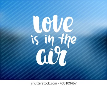 trendy hand lettering poster. Hand drawn calligraphy. Template post card. concept handwritten motivation poster on blue lines "love is in the air".  Abstract de focused sky. blurred background