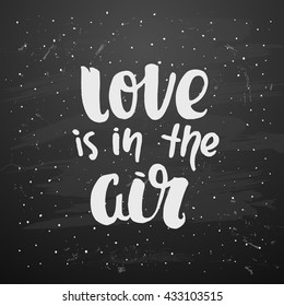 trendy hand lettering poster. Hand drawn calligraphy.  Template post card on black background. concept handwritten poster. chalkboard art "love is in the air"  creative graphic