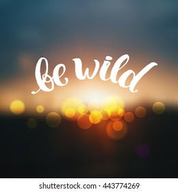 trendy lettering poster. Hand drawn calligraphy  "be wild" creative graphic template brush fonts inspirational quotes. motivational illustration on blurred background sunset  with bokeh effect