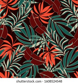 Trendy seamless tropical pattern with bright orange and green plants and leaves on a Burgundy background. Seamless exotic pattern with tropical plants. 
Trendy summer Hawaii print.