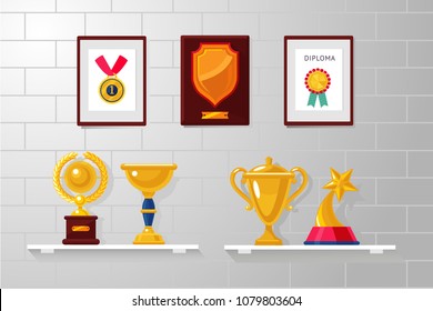 Trophy and awards collection on a white wall. Diplomas, competition prizes and cups.