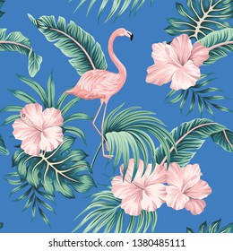 Tropical pink hibiscus and flamingo floral green palm leaves seamless pattern blue background. Exotic jungle wallpaper.