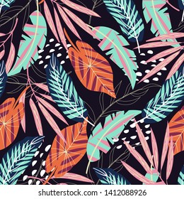Tropical seamless pattern with leaves and plants on a dark background. Vector design. Jungle print. Textiles and printing.