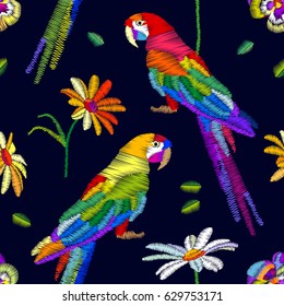 Tropical summer. Seamless vector pattern with parrots and flowers. Stylized embroidered texture.