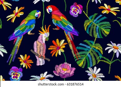 Tropical summer. Seamless vector pattern with parrots, flowers and palm leaves. Stylized embroidered texture. Vintage motifs.