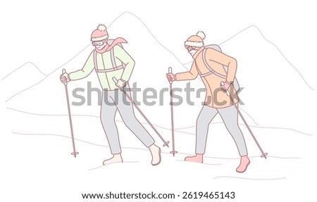 Two adventurous hikers trek through breathtaking snowy mountains, equipped with poles and winter gear for cold