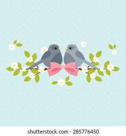 Two birds sitting on blooming branches with pink bow. 