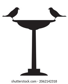 Two birds are standing on a bird bath staring at each other in silhouette