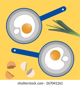 Two blue pans with the poached eggs, broken eggshells and part of the leek on the yellow background.