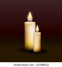 Two burning candles on a dark background