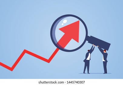 Two businessmen use magnifying glass to magnify arrows