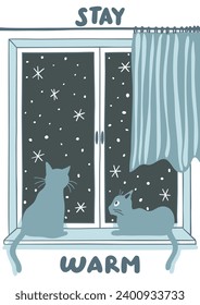 Two cats seating on the window looking at the snow outside