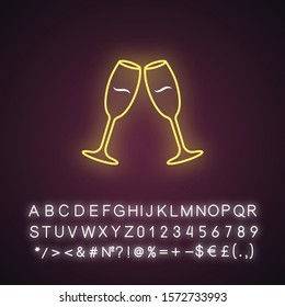 Two clinking wine glasses yellow neon light icon. Champagne flutes. Glassfuls of alcohol drink. Wine service. Celebration. Glowing sign with alphabet, numbers and symbols. Vector isolated illustration