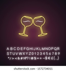 Two clinking wine glasses yellow neon light icon. Glassfuls of alcohol drink. Wine service. Celebration. Toast. Cheers. Glowing sign with alphabet, numbers and symbols. Vector isolated illustration