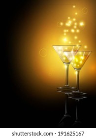 Two cocktail glasses on black background with golden glowing and sparks.
