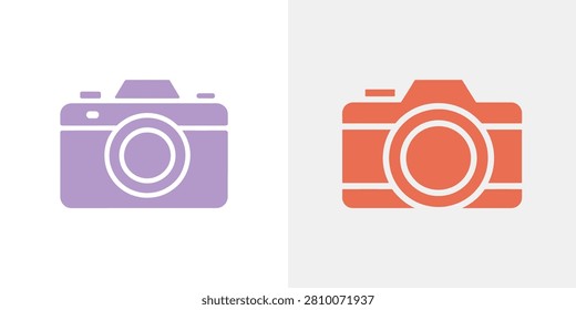 Two of a digital camera with a lens, one in light purple and one in coral orange, isolated on a light gray background, for web use
