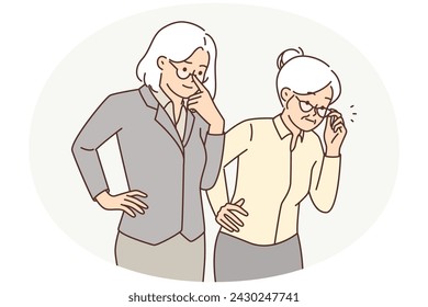 Two elderly women in business clothes carefully look to side watching work of young employees. Elderly gray-haired women adjusts glasses in front of eyes, they are curious after seeing unusual object