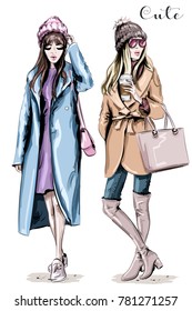 Two fashion women. Hand drawn stylish beautiful women in winter clothes. Fashion winter outfits. Sketch.