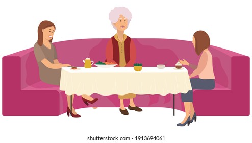 Two girls and a elderly gray-haired woman are sitting at a table on a big red sofa. Consultation with a psychologist in a cafe with cups of tea and cakes. Grandmother communicates with two women